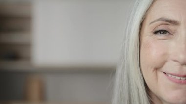 Close up macro detail half female wrinkled face caucasian old woman blonde grey-haired mature housewife lady wise granny grandmother looking at camera smiling posing in studio elderly age rejuvenation