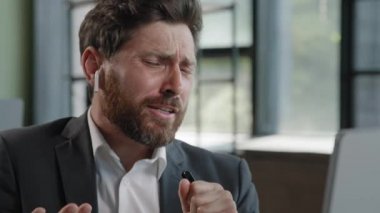 Funny adult mature 40s company CEO manager man in office break work listening music audio online radio in wireless headphones singing in pen like microphone loud at workplace bearded businessman fun
