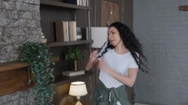 Happy energetic woman housewife homeowner dancing at home imitating drumming cleans apartment cleaning up shelf young excited sensual girl dances to rhythmic music enjoying carefree pastime on weekend