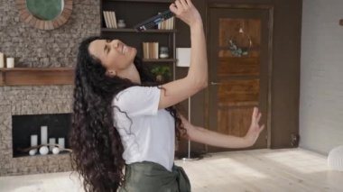 Funny energetic girl sings song using TV remote as microphone young carefree woman dancing to music singing having fun at home on weekend excited female blogger records vlog enjoys leisure time alone