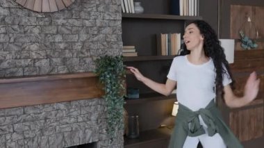 Young energetic woman housewife dancing in living room having fun cleaning enjoying cleanliness in house excited funny girl active moves to rhythmic music celebrates success fun home routine concept