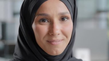 Headshot of young attractive arab woman in hijab looking at camera beautiful muslim girl with natural make-up posing indoors portrait happy islamic female smiling with healthy white teeth close-up