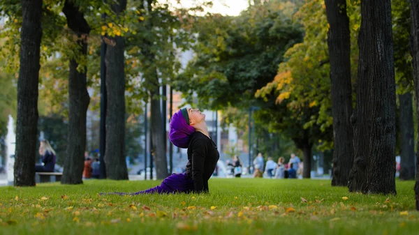 Muslim athletic woman practice yoga sun salutation in park on grass morning routine up facing dog pose asana for body care healthy spine stretching flexibility. Girl in hijab productive practicing