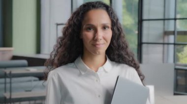 Female portrait closeup attractive woman perspective worker manager secretary representative agent looking at camera standing in office young successful confident hispanic businesswoman posing indoors