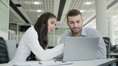 Young positive woman sales agent shows product on laptop to man client tells about profitable offer girl recruit office worker tells mentor development of new progressing strategy planning workflow