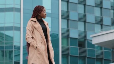 Young stylish woman looks away waiting for meeting stands in business center of city confident successful serious businesswoman turns to camera fashion girl model posing outdoors looking at camera
