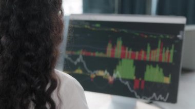 View from back young woman office worker financial analyst statistician studying sales graph shown on diagram on computer analyzes market statistics using infographic makes forecast result trading