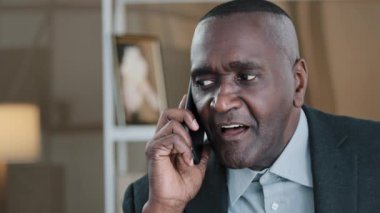Closeup male wrinkled African American adult old senior mature businessman elderly citizen man talking mobile phone talk remote distant negotiation speaking conversation communication use smartphone