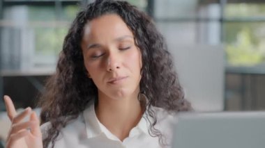 Close-up relaxed carefree balanced businesswoman listening to calm music with closed eyes at workplace sings enjoys favorite song young carefree woman makes pause relax listens to pleasant audio track