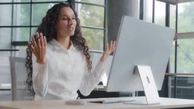 Young attractive woman office worker sales agent communicates with client via video call discussing benefits product negotiates online conference using webcam explains details of project to colleagues