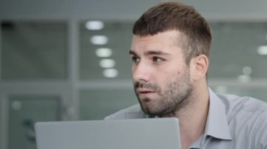 Close-up young puzzled pensive businessman in confusion works on laptop thinks in search of inspiration problem solving creates business project startup develops strategy looking for new ideas decides