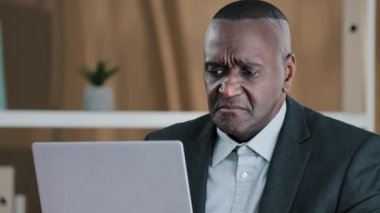 Upset frustrated African American adult old senior mature businessman elderly citizen man looking in laptop screen with sad lost failure suddenly female hands give money dollars banknote finance prize