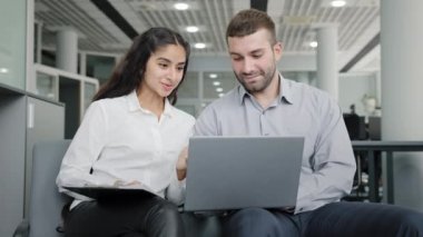 Young man and woman office workers creative team colleagues discussing online project develop strategy using laptop exchange ideas talks in workplace businesswoman consulting client business meeting