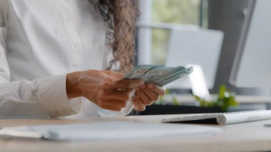 Unrecognizable young woman accountant counts cash at workplace female office worker bank cashier calculates salary with paper dollar bills monthly calculation finance budget savings currency exchange