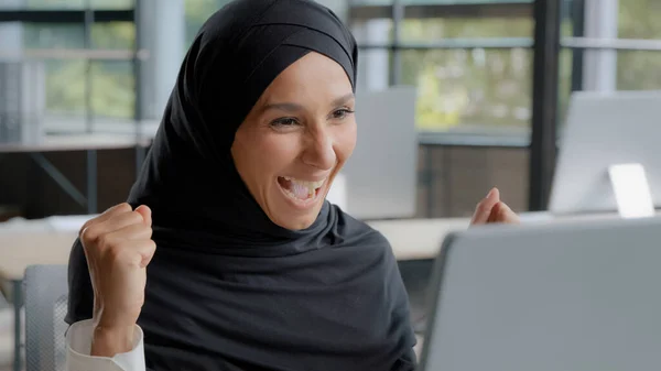 Young excited arab woman checking email on laptop concentration reading gets good news amazed happy businesswoman winner celebrating victory rejoices in success feels joy receives reward career growth