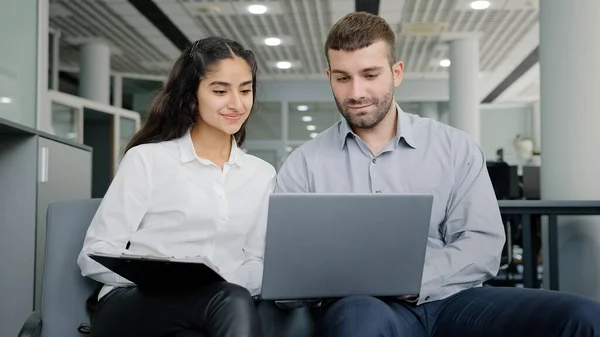 Young man and woman office workers creative team colleagues discussing online project develop strategy using laptop exchange ideas talks in workplace businesswoman consulting client business meeting