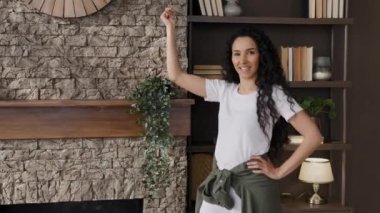 Happy energetic woman performing funny moves to music active female blogger recording dance vlog rhythmic dancing jumping on couch lies relaxed on sofa enjoying rest advertising comfortable furniture