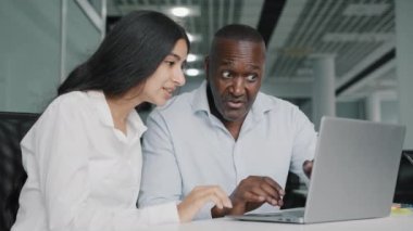 African male businessman financial lawyer agent consultant discuss internet project arab young female trainee consult client explaining insurance at office meeting two diverse colleagues work together