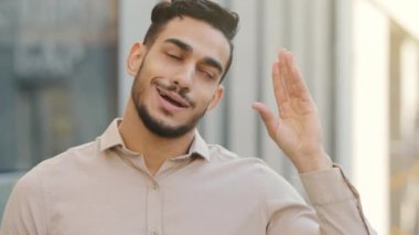 Close up emotional disappointed grimacing male portrait outdoors in city Hispanic Arabian Indian bearded bored business man disappointed showing bla-bla-bla sign with hand blah gesture empty promises