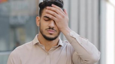 Close up portrait upset looser sad frustrated disappointed failure Arabian Hispanic Indian businessman face palm reaction stress with problem bearded man lost trouble unpleasant worry outdoors in city
