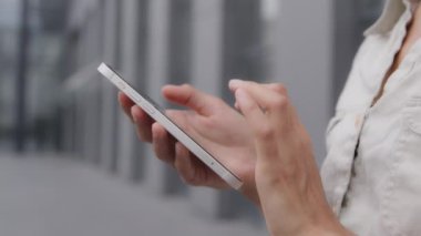 Close-up females hands holding phone. Fingers dialing number on smartphone screen. Unrecognizable woman using mobile application to search for information network calls taxi chatting outdoors in city