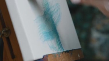 Close-up white canvas on easel unrecognizable painter artist designer paints with paint brush blue stripe painting with acrylic abstract picture art therapy hobby drawing create picture creative idea