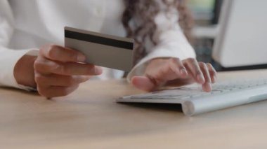 Close-up of female hands holding credit card entering data making purchases in online store paying for goods using computer banking application pays invoice secure payment uses fast money transfer