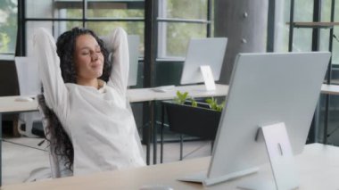 Relaxed woman manager taking break at workplace holding hands behind head resting after completing work sitting at desk dreaming with closed eyes enjoying relaxation feels satisfaction by work done
