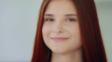 Studio portrait of beautiful redhead ginger girl teenage caucasian young model pretty face looking at camera smiling posing with friendly sight dark eyes flawless skin no cosmetic natural youth beauty