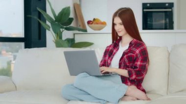 Young redhead teenager preteen ginger schoolgirl freelancer works on laptop chatting at home room sends messages makes online order purchases food delivery watches movies shows ok gesture recommend