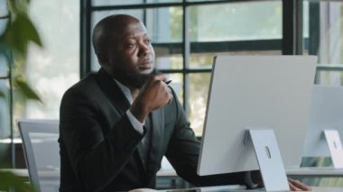Thoughtful dreamy african man executive worker teacher male team leader has dilemma question thinking decision brainstorming create startup project business strategy turn pen in hand ponder new idea
