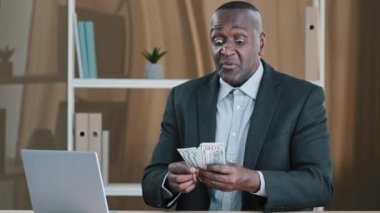 African old male boss banker company CEO investor mature senior businessman counting money in office biracial success wealthy man holding dollars salary accounting savings budget cash thinking pensive