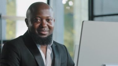 African adult businessman happy plus size guy satisfied with computer app typing on laptop in office smiling recommend good choice fine idea sign thumb up excellent result agree approval hand gesture
