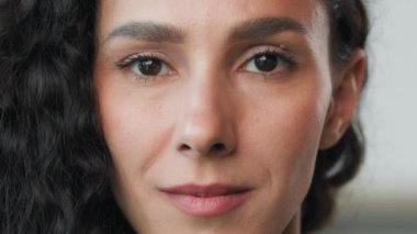 Portrait gorgeous beautiful brunette curly attractive woman hispanic young girl with flawless perfect skin natural day makeup looking friendly at camera soft smiling. Close up female face arabic model