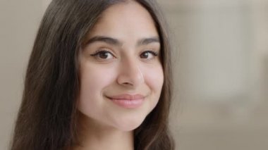 Close up portrait beautiful girl arabian oriental young brunette pretty millennial woman female face with perfect skin black eyeliner on eyes natural makeup posing at home smiling healthy white smile