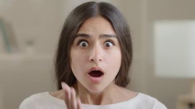 Afraid emotional girl brunette woman negative shocked frightened arabian young lady hold head with hands open mouth feel horror terrified facial emotion looking at camera panic confusion bad reaction