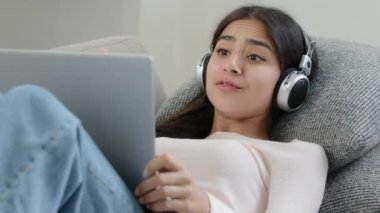 Arabian carefree female singer student relaxed freelancer girl wears headphones listen pop music on laptop sing favorite song enjoy vocal hobby musical radio rhythmic playlist having fun rest at home
