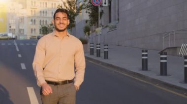 Indian happy smiling guy businessman manager banker entrepreneur employee smile toothy cheerful walking city road walkway street outdoors. Confident adult bearded man walks going to office at morning