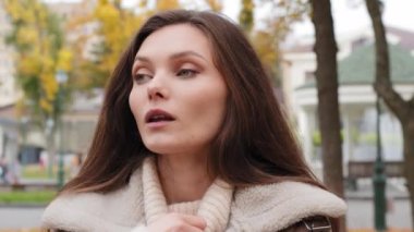 Caucasian girl stand alone in autumn park thoughtful unsure puzzled young woman has dilemma question hold hand to chin come up with idea create plan feeling inspiration find answer raise index finger