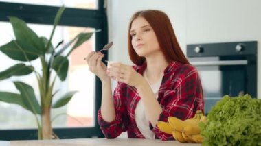 Vegetarian caucasian woman redhead female vegan girl sit in kitchen eat dairy creamy desert on breakfast healthful morning snack yogurt with minimal calorie keep diet taste delicious brunch bodycare
