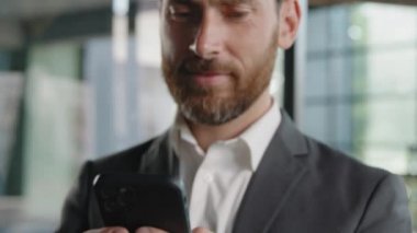 Moving footage closeup male hands holding smartphone bearded smiling happy success businessman 40s man typing chatting with phone in mobile app make order online internet store thinking about choice