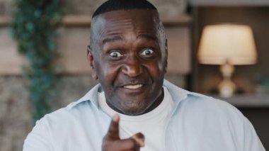 Annoyed temperamental african american crazy senior angry man threat looking at camera make warn gesture by finger show facial displeasure rage emotion furious negative attitude irritated talk bulling