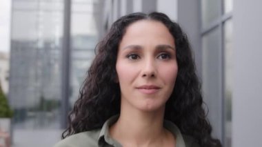 Closeup headshot portrait happy smiling toothy cheerful success lady businesswoman 30s director leader boss female girl with curly long hair woman walking going moving in city looking away with smile