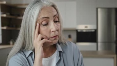 Disappointed sad elder caucasian woman grey-haired lady mature miserable woman hold hand on head massaging temple feel unwell health problem high blood pressure worried about difficult period of life