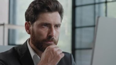 Portrait thoughtful pensive bearded 40s male businessman working on pc computer at modern office thinking about idea business project problem solution focused man employee has difficulties with job