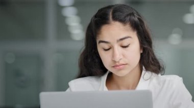 Close-up young sad tired woman manager looking at laptop screen in office feeling exhausted headache fatigue after using computer working overwork girl massages bridge nose suffering from eye strain