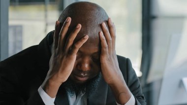 Sick exhausted african man suffer from headache migraine syndrome hold head by hands tired overworked american adult disappointed unhealthy businessman feel discomfort tension pressure mental fatigue