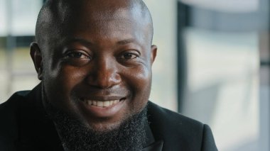 Happy satisfied glad african american male businessman plus size face bearded adult man with dark skin employee worker educator smiling white healthy toothy smile stare turning head looking at camera