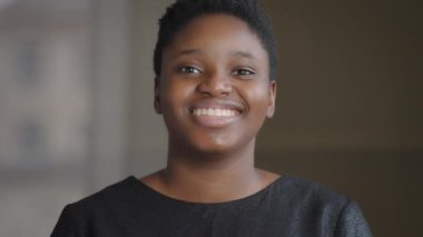Ön cephe portresi. Mutlu, dişlek, beyaz, sağlıklı dişlerle gülümseyen, Afro-Amerikan, 20 'li yaşlarda, melez, kısa saçlı, doğal makyajlı bir kız.