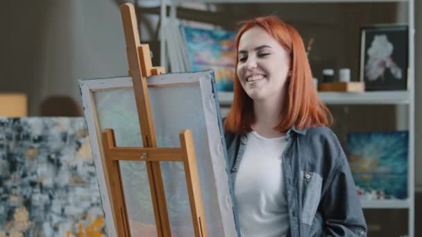 陽気な屈託のない白人女性アーティスト赤い髪の女の子の画家は アートスタジオで絵を描く音楽のダンスに耳を傾ける作成します — ストック動画